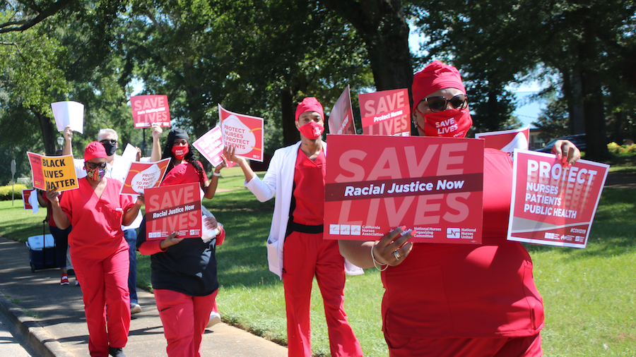 Nurses holds signs "Racial Justice Now" and "Protect Nurses"