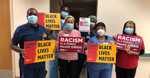 Nurses hold signs "Racism is a public health crisis"