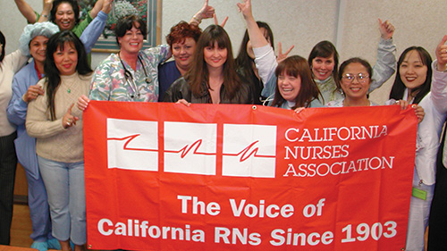 Group of nurses holding CNA banner with raised fists