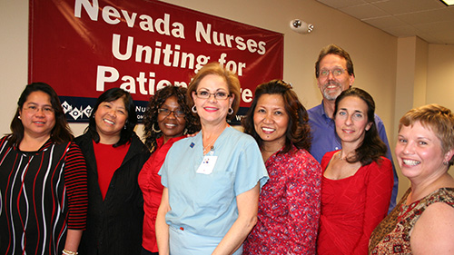 Eight nurses stand in front of banner "Nevada Nurses Uniting for Patient Care"