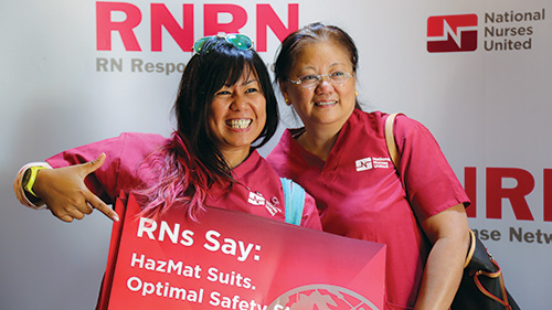 Two nurses holding signs for Ebola preparation