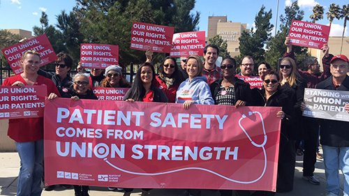 Nurses outside hold banner "Patient Safety Comes from Union Strength"