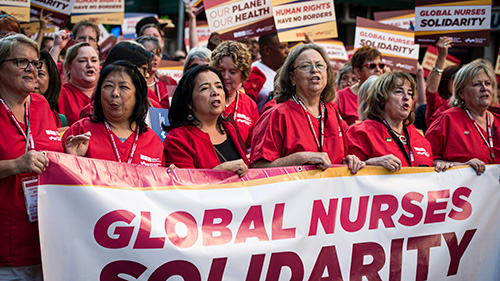 Nurses marching holding banner "Global Nurses Solidarity"