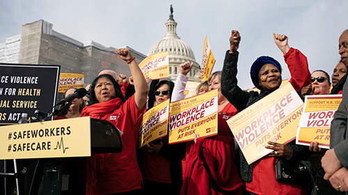 Nurses outside U.S. Capitol building with raised fists, signs that say "Workplace Violence Effects Everyone"