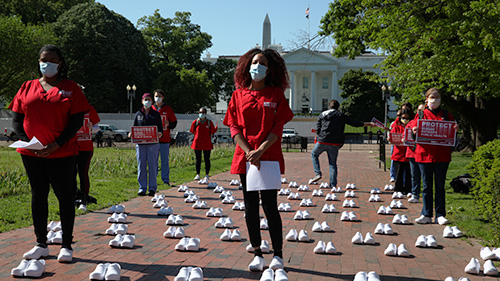 Group of nurses stand outside The White House surrounded by empty white shoes