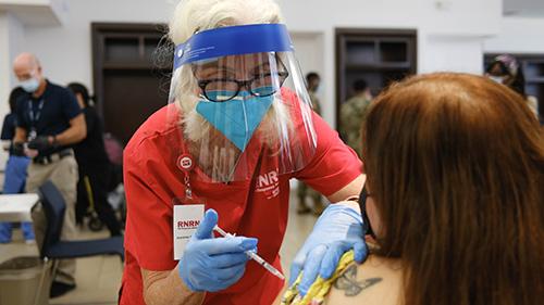 Nurse wearing faceshield administiring vaccine