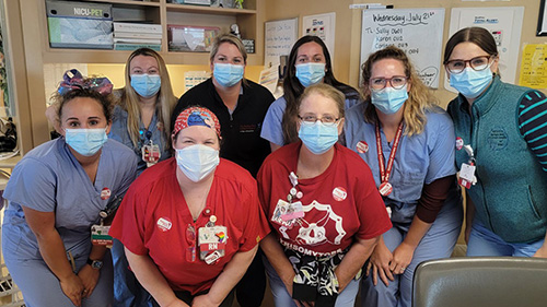 Group of eight nurses inside hospital posing for picture