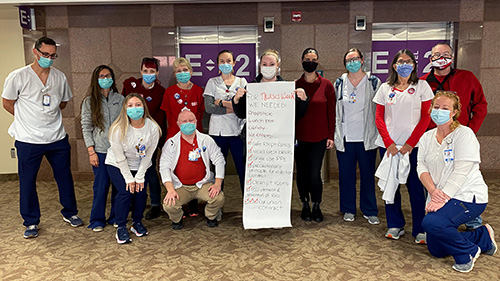 Large group of nurses inside hospital holding long list or bragaining demands