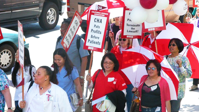 Group of nurses holding signs "CHA puts profits over patients"