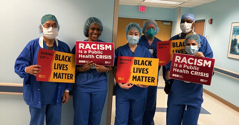 Nurses hold signs "Racism is a Public Health Crisis"