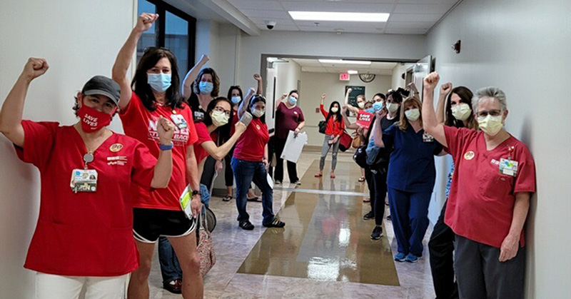Large group of nurses in hallway old raised fists