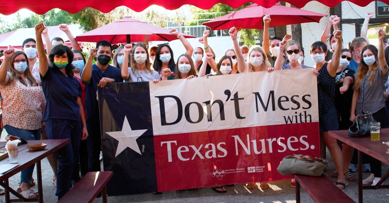 Large group of nurses outside hold sign "Don't mess with Texas nurses"