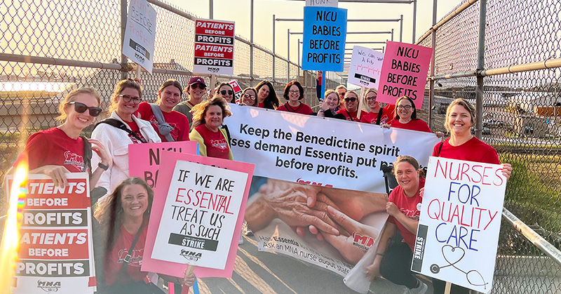 Large group of nurses outside hold signs