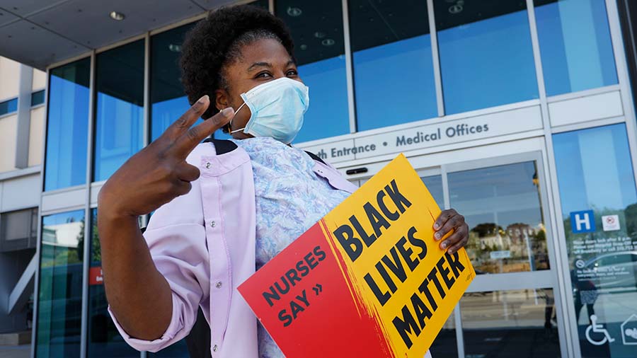 Nurse holds sign "Nurses Say: Black Lives Matter"