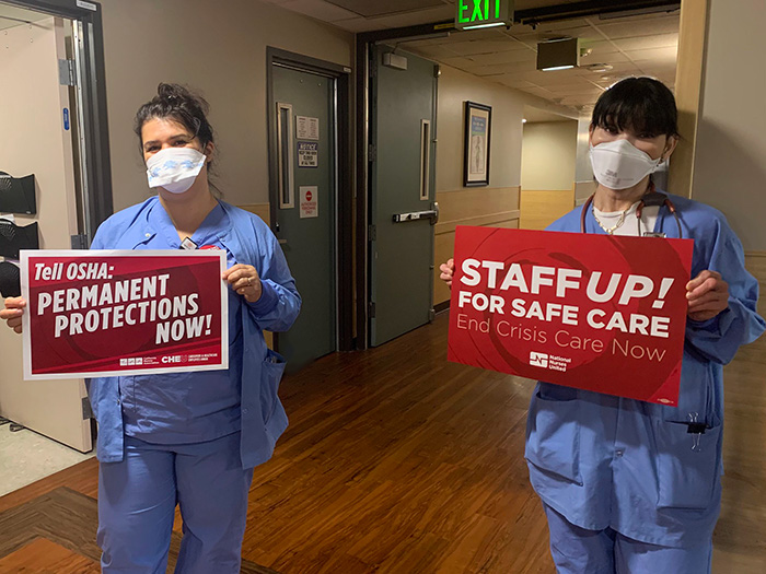 Nurses hold signs calling for a permanent OSHA standard