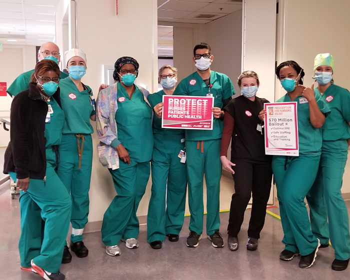 Group of nurses inside hospital hold sign "Protect Nurses, Patients, Public Health"