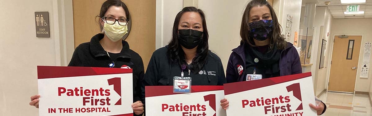 Three nurses inside hospital hold signs "Patients First"