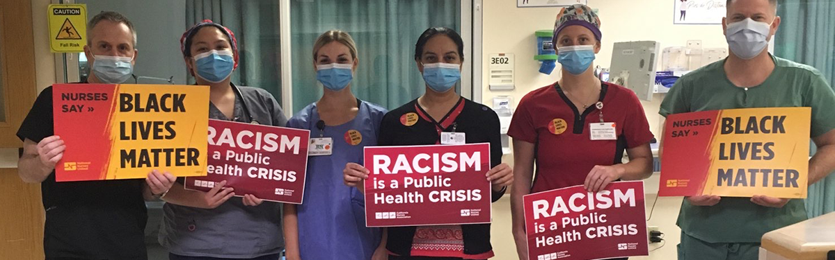 Nurses hold signs "Racism is a public health crisis"