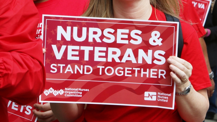 Nurse holds sign "Nurses & Veterans Stand Together"