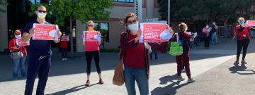 Nurses hold signs "PPE is disposable, nurses are not"
