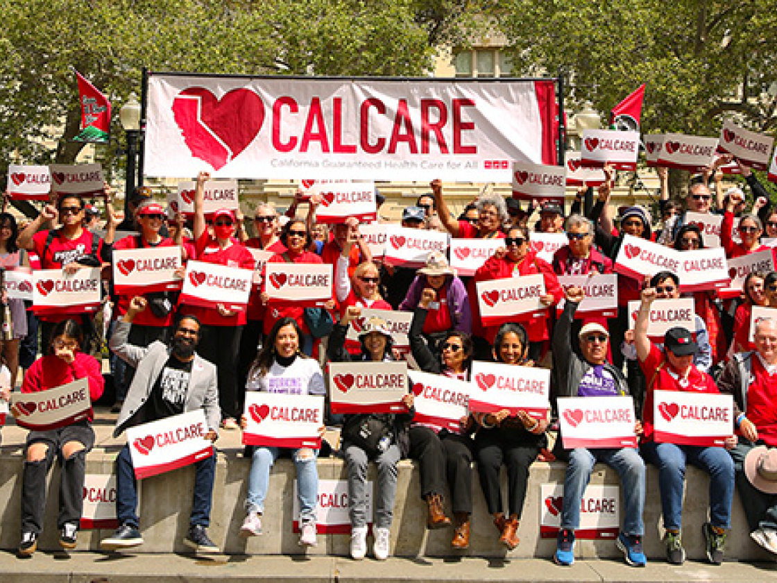 Large group of people holding CalCare signs and banner