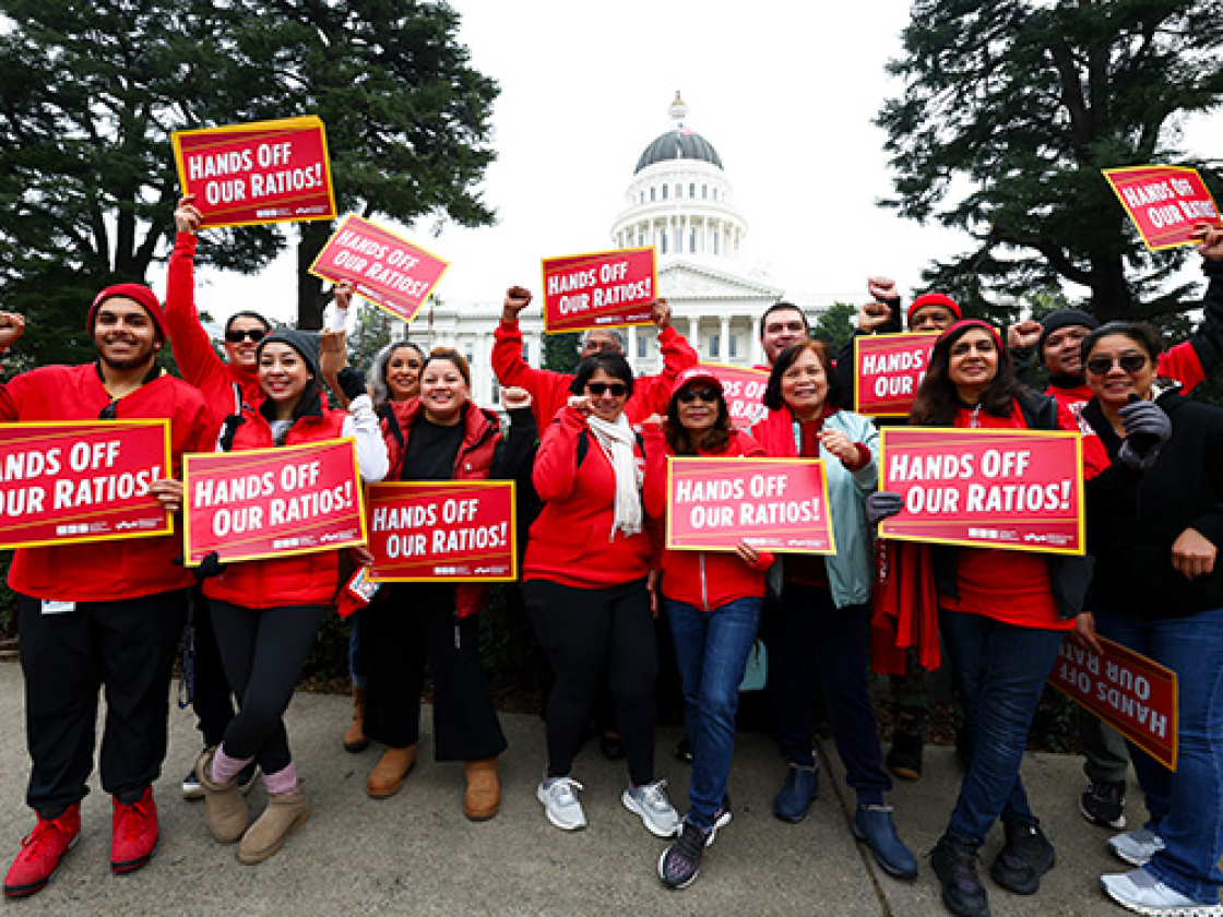 Group of nurses outside California State Capitol building holding signs "Hands Off Our Ratios"