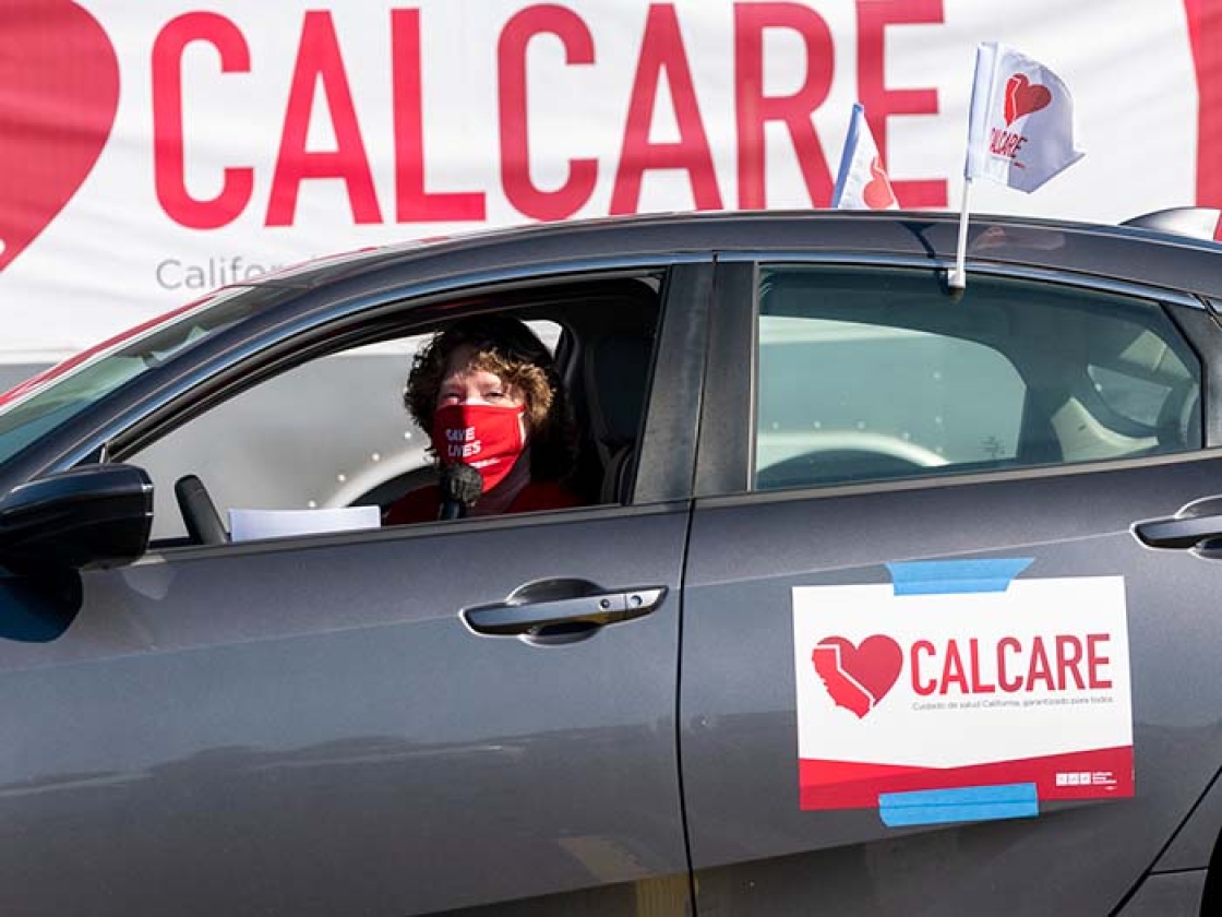 Nurse inside car displaying sign "CalCare"