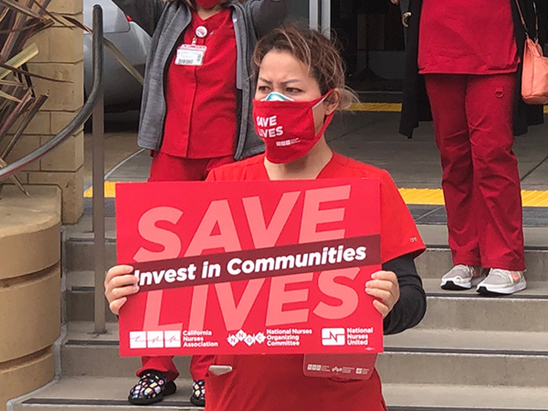 Nurse hold signs "Invest in Communities"