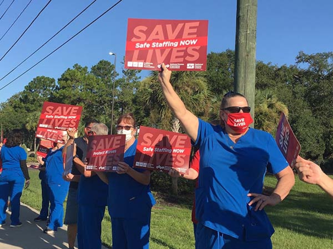 Nurse holds sign "Save Lives: Safe Staffing Now"