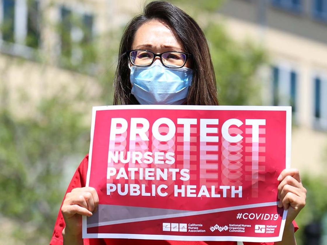 Nurse hold signs "Protect Nurses, Patients, Public Health"