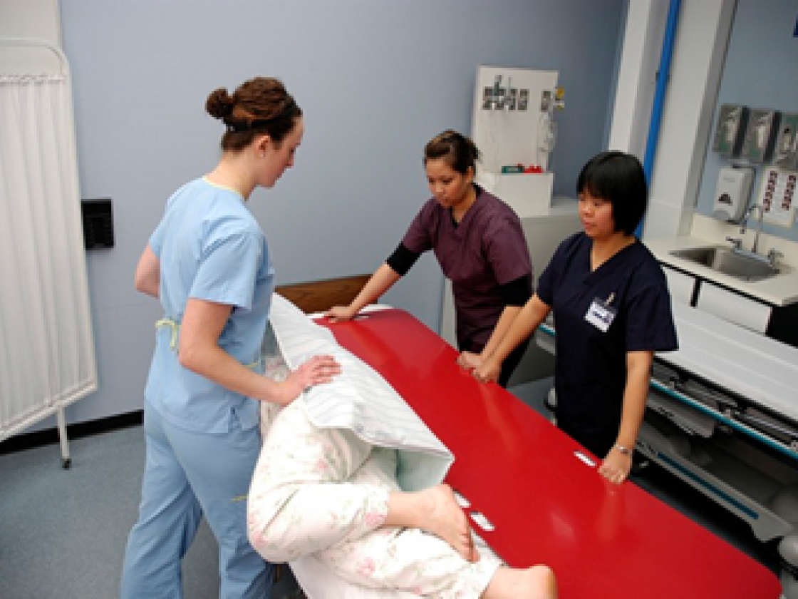 Nurses transfering patient to bed