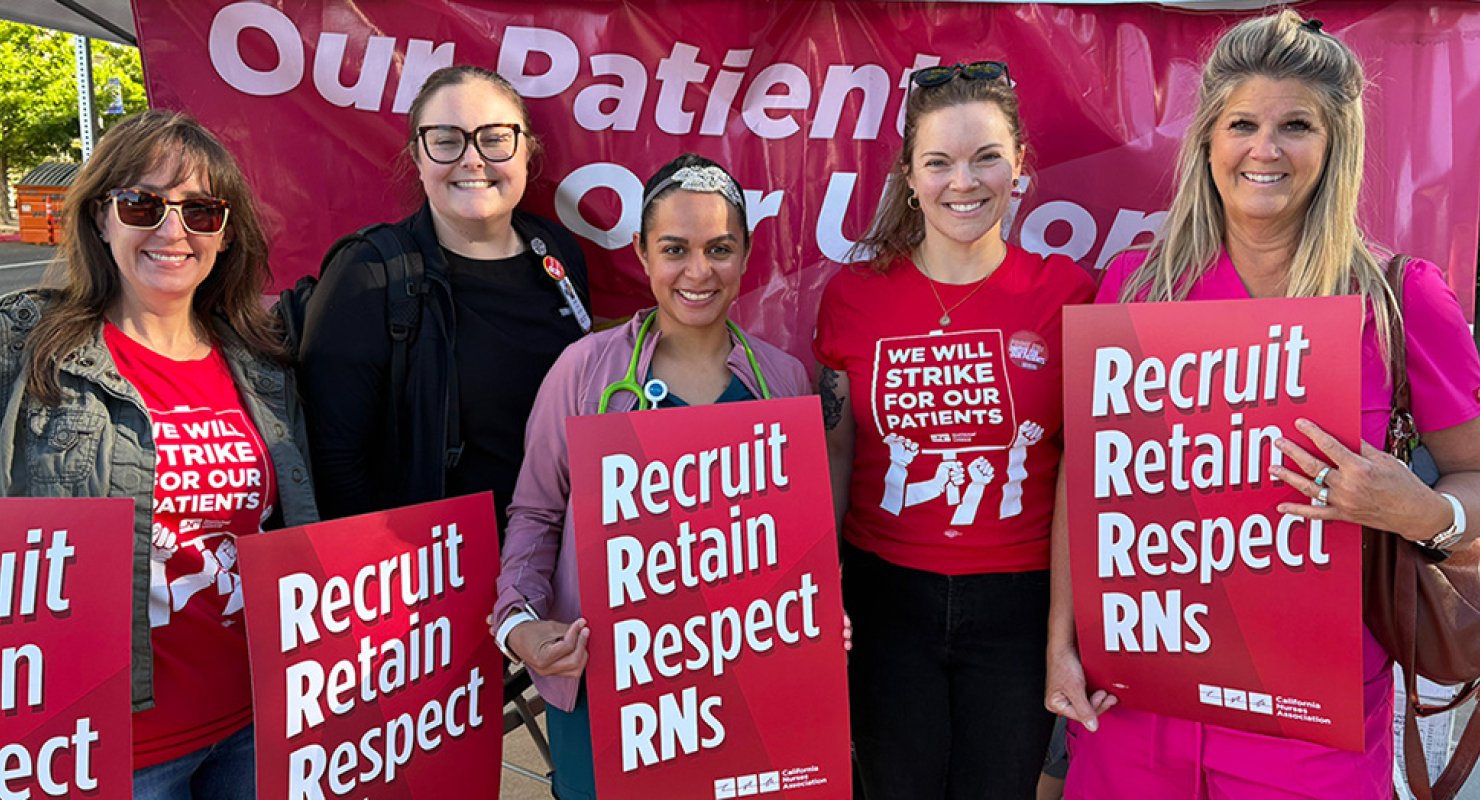 Five nurses, outside, smiling, side-by-side, holding signs "Recruit, Retain, Respect RNs"