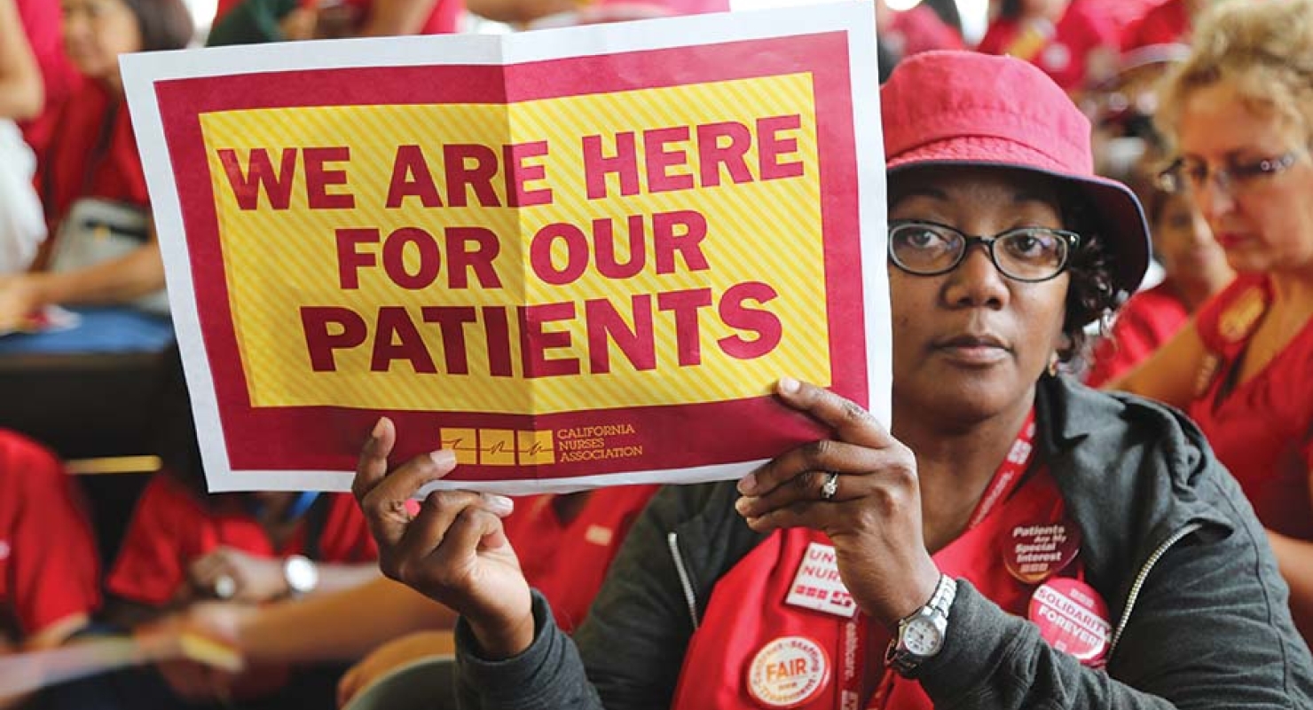 Nurse holds sign "We are here for our patients"