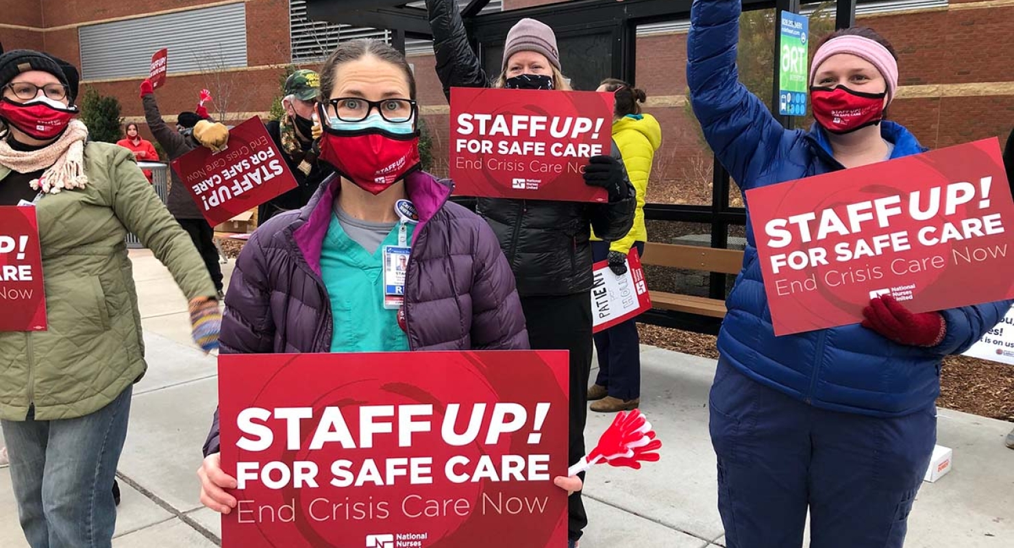 Nurses hold signs "Staff Up for Safe Care"