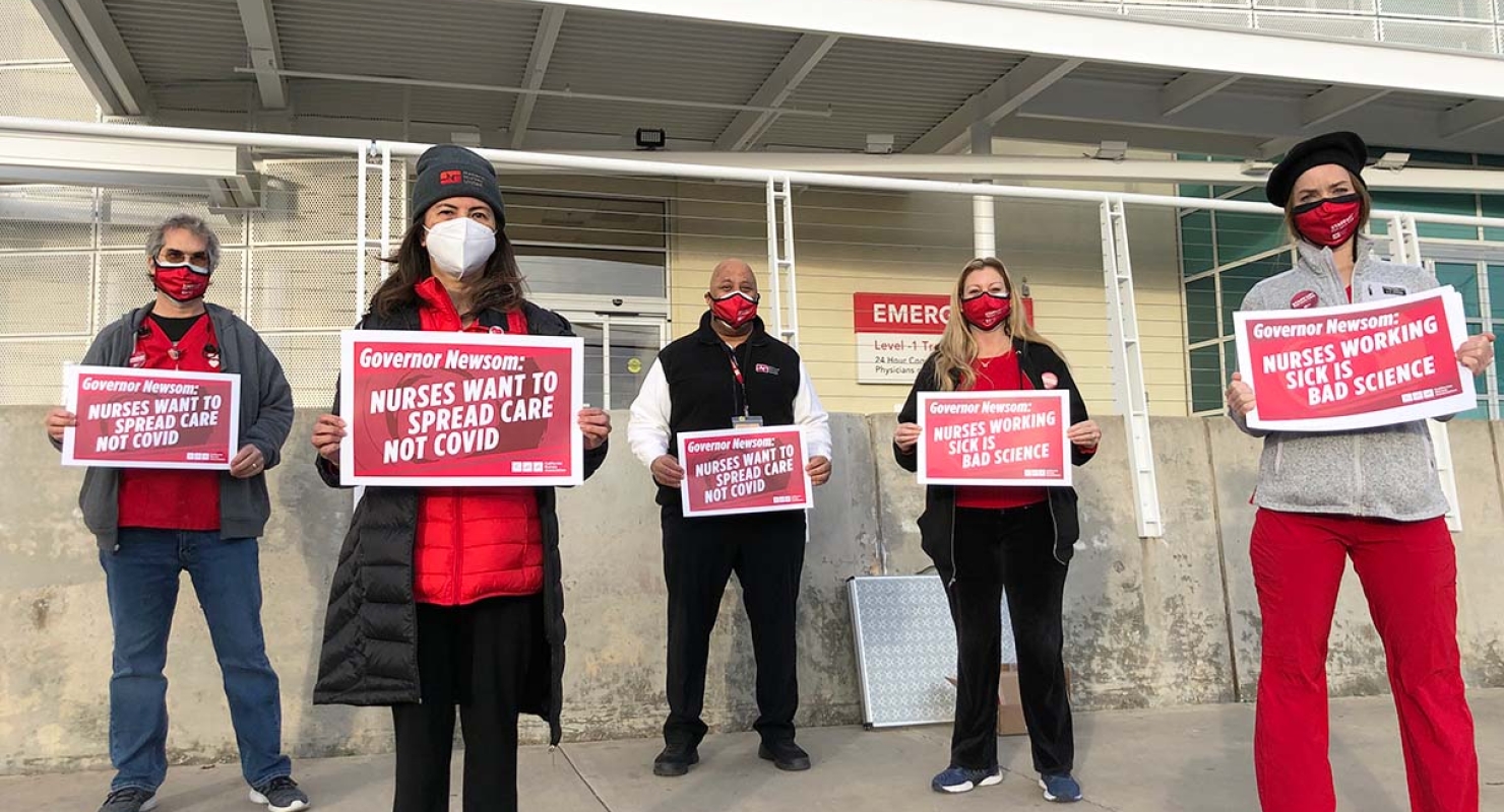 Nurses hold signs "Spread Care Not Covid"