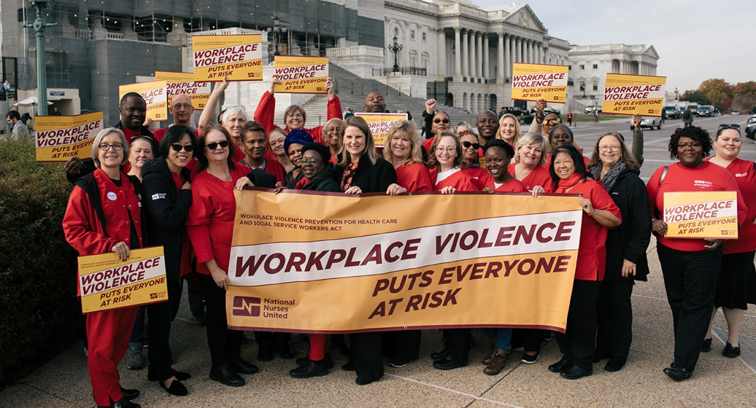 Large group of nurses outside the Capitol Building with signs calling for workplace violence prevention.