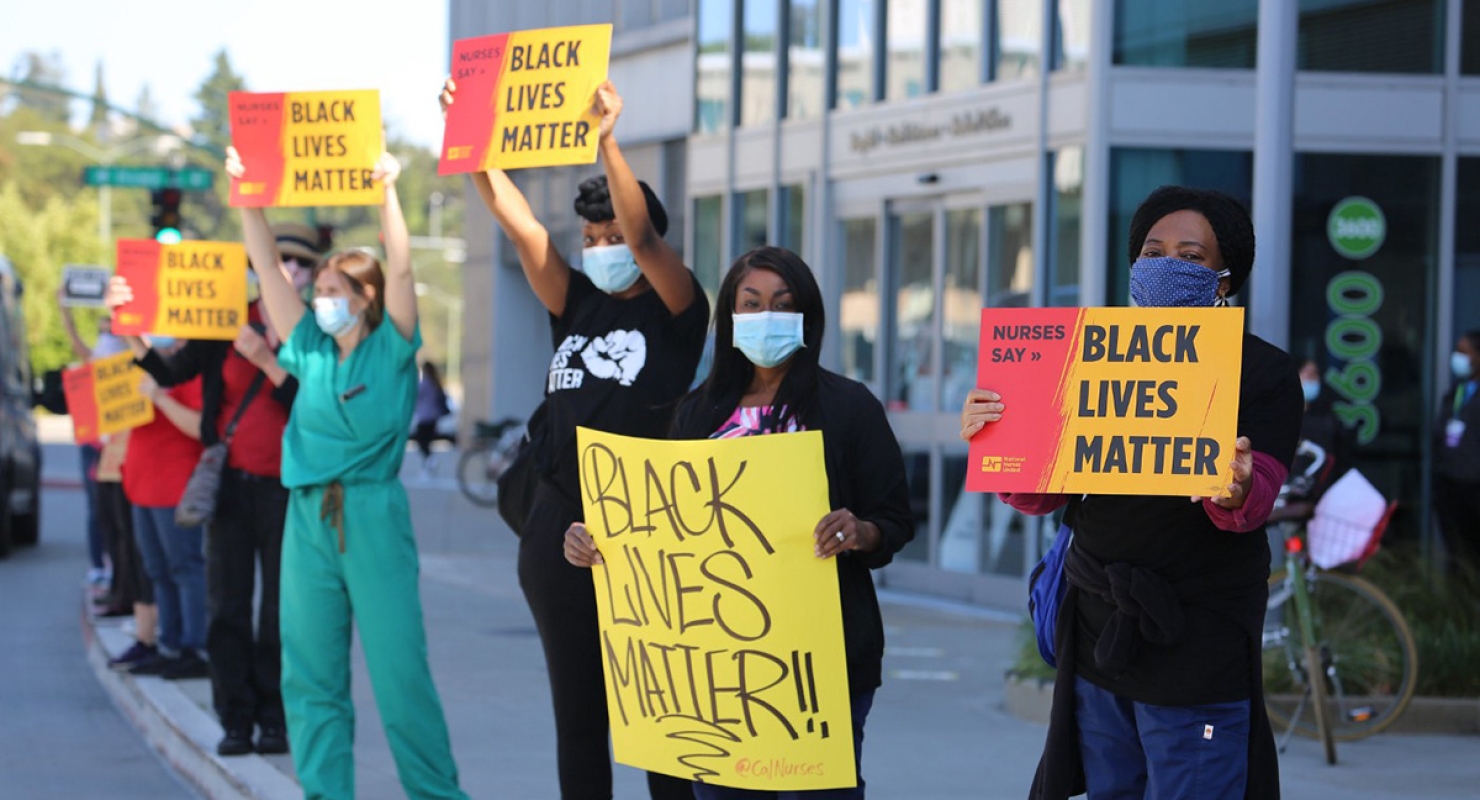 Nurses outside hospital hold signs "Nurses Say: Black Lives Matter"