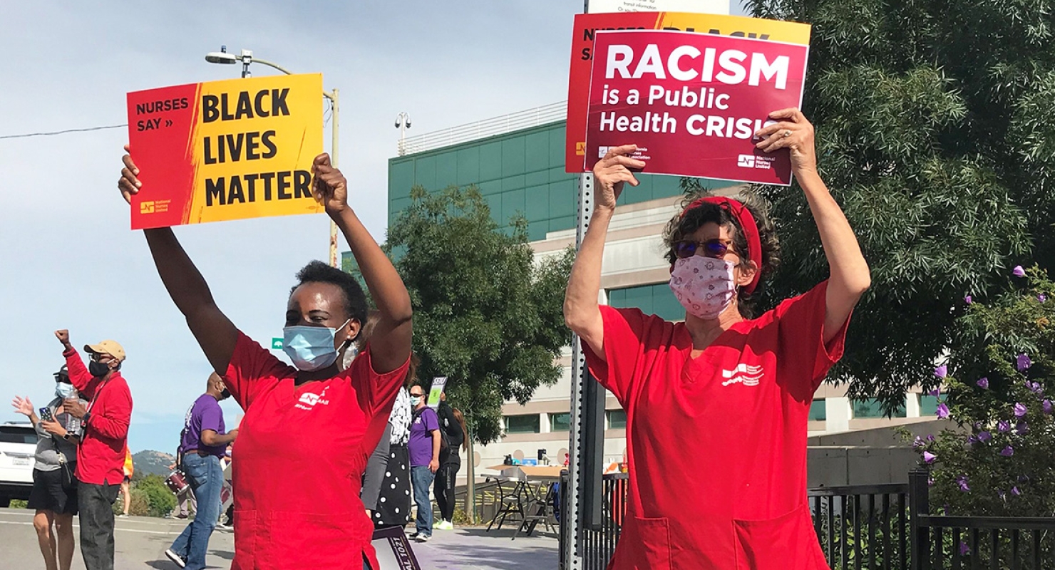 Two nurses holding signs "Nurses Say Black Lives Matter" and "Racism is a Public Health Crisis"
