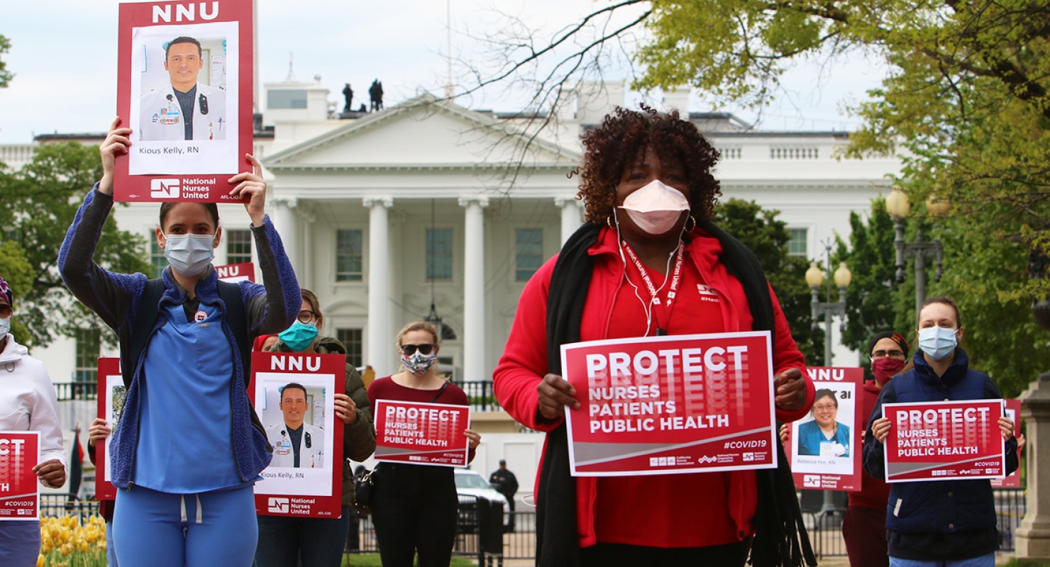 Masked nurse outside White House hold signs "Protect Nurses, Patients, Public Health"