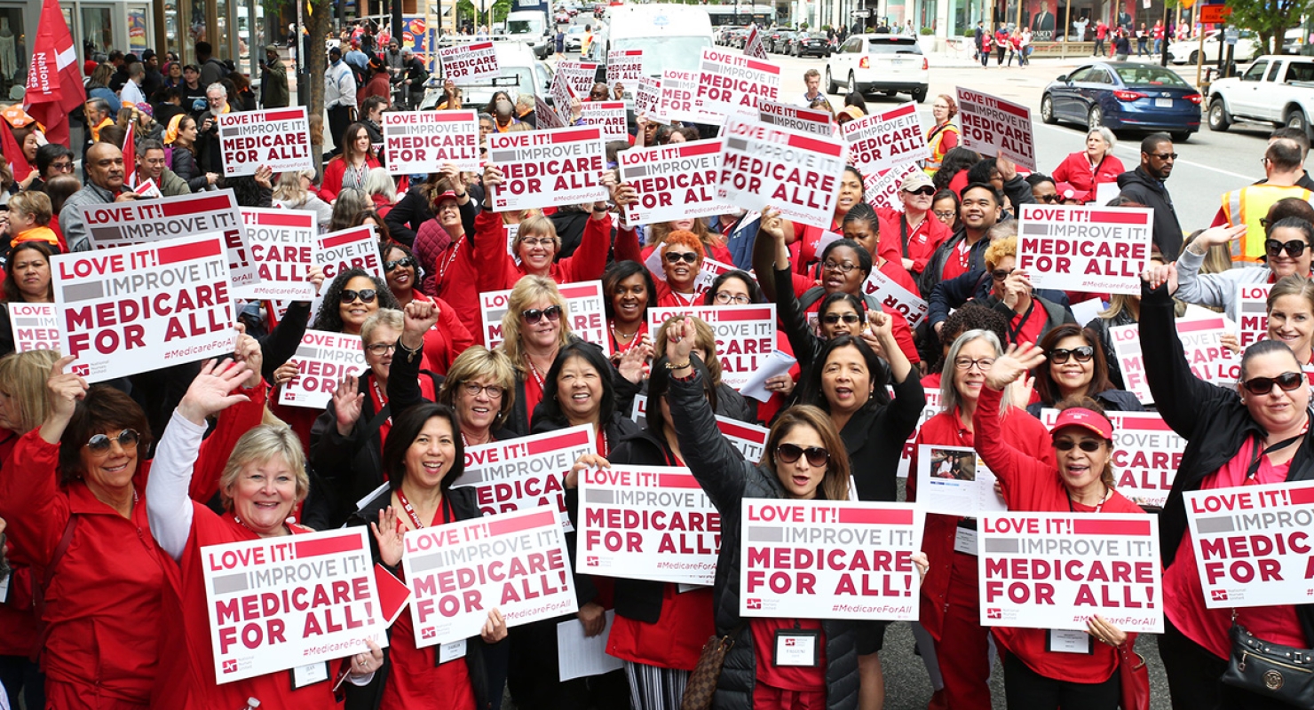 Large group of nurses holdings signs "Love it! Improve it! Medicare for All!