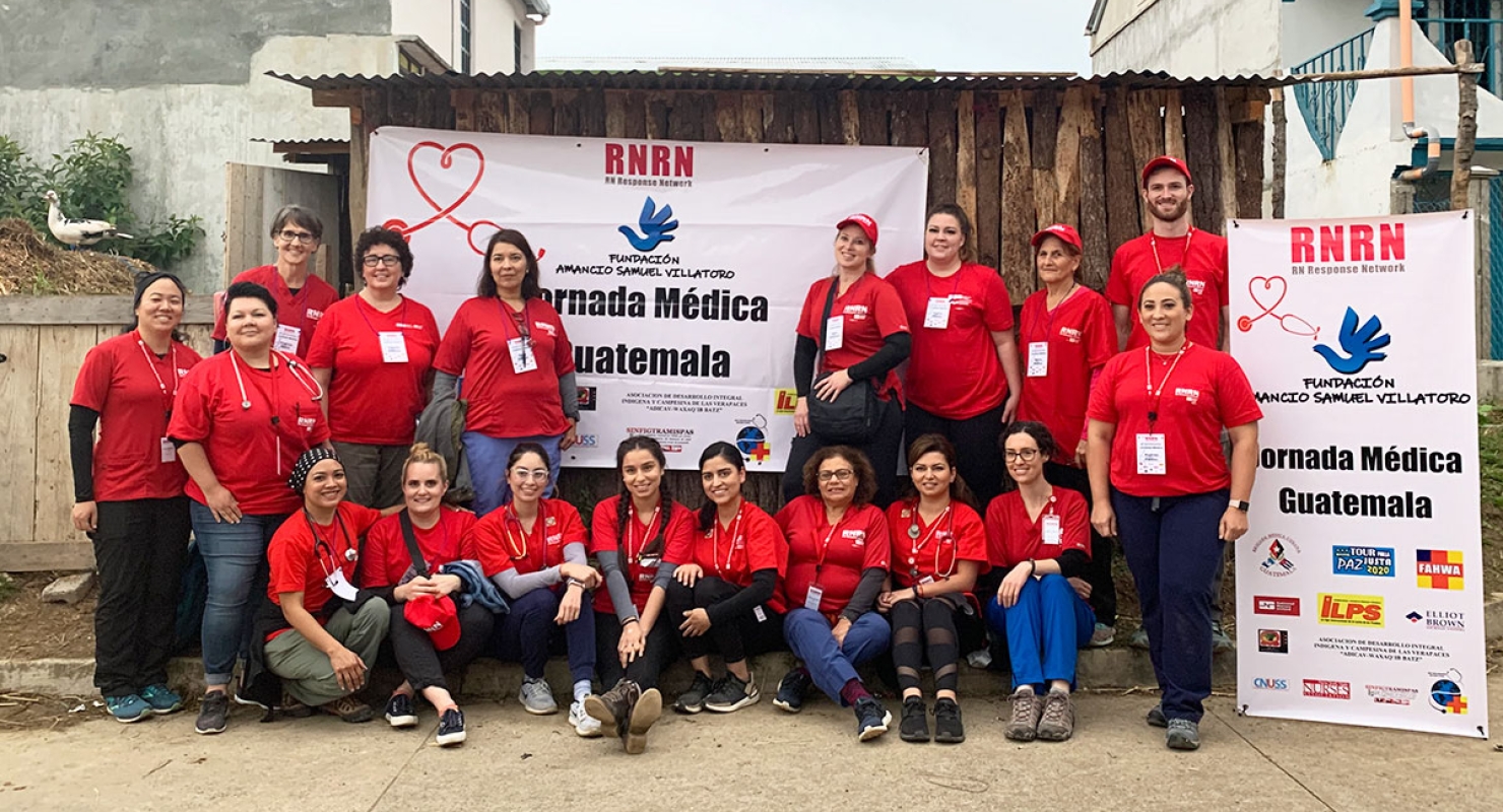 Group of nurses in red scrub shirts holding RNRN banner