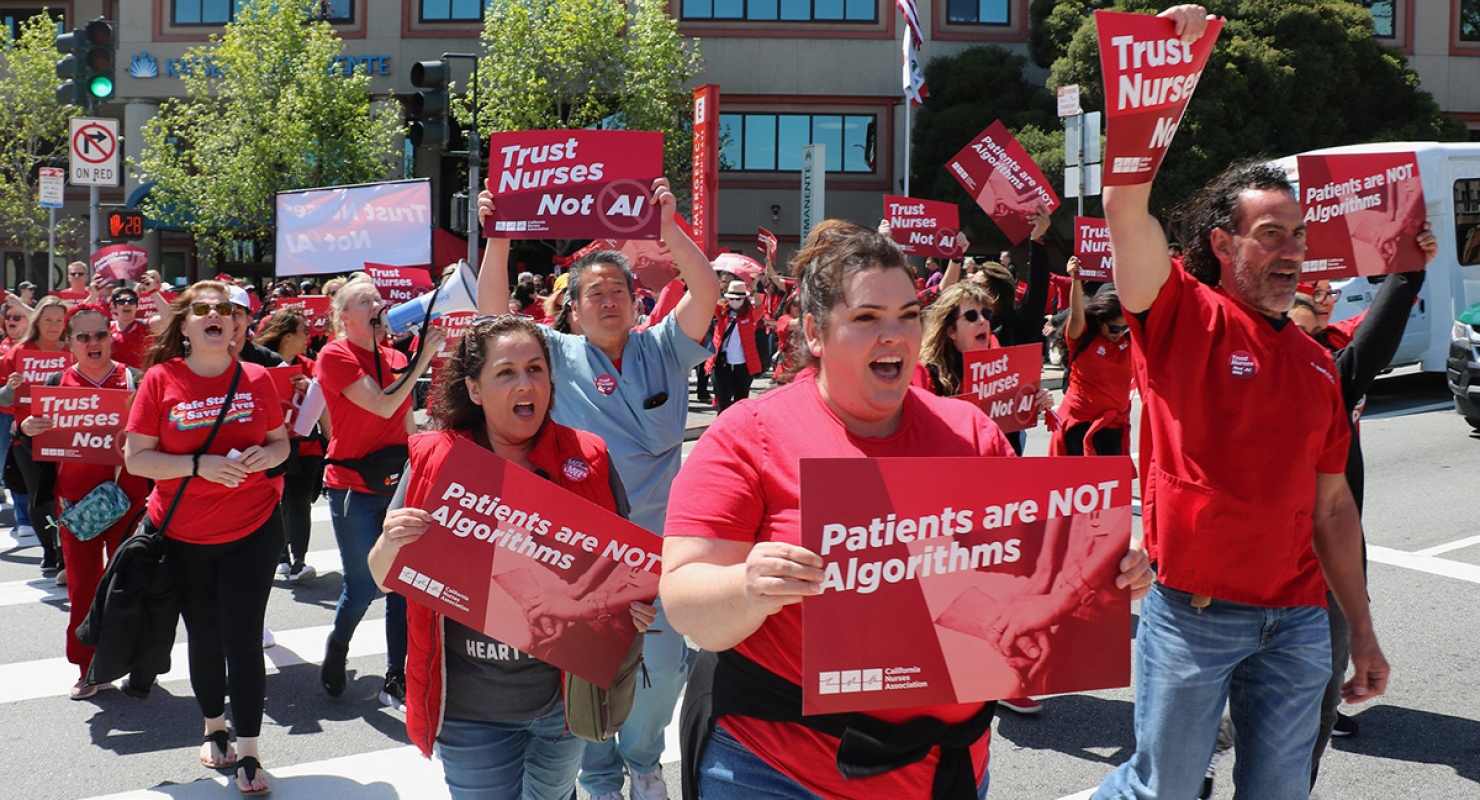 Nurses marching holding signs "Trust Nurses, Not AI" and "Patients Are Not Algorithms"