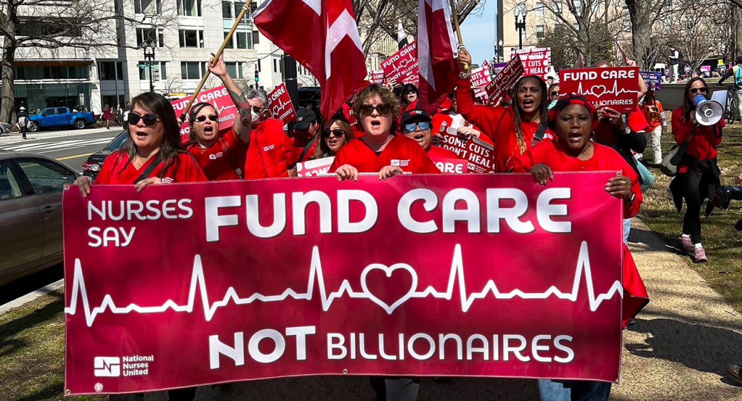 Nurses marching, holding banner "Fund Care NOT Billionaires"
