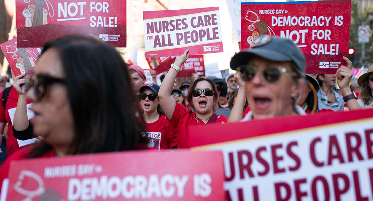 Nurses marching holding signs "Nurses Care for All People"