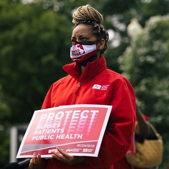 Nurses hold signs "Protect Nurses, Patients, Public Health"