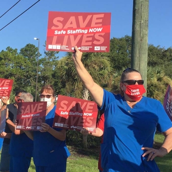Nurses outside hold signs "Safe Staffing Now"