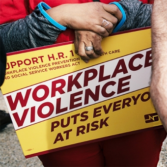 Nurse holding sign "Workplace violence put everyone at risk"