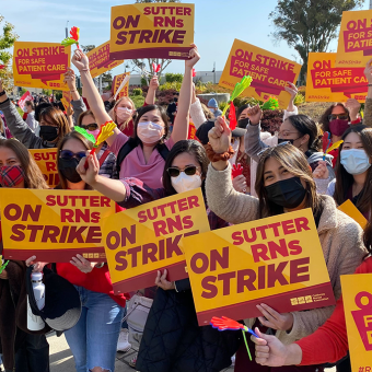 Large group of nurses hold signs "On Strike"