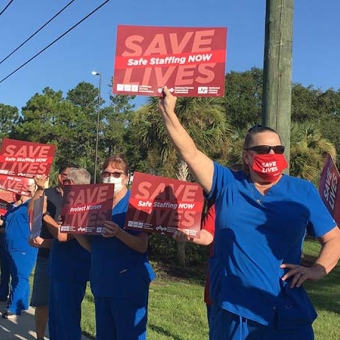 Nurse hold sign "Save Lives: Safe Staffing Now"