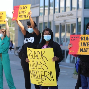 Nurses outside hospital hold signs "Nurses Say: Black Lives Matter"